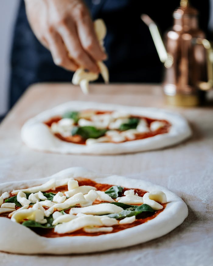 about-01 A close-up of a hand preparing Neapolitan pizza with fresh toppings in a London kitchen.
