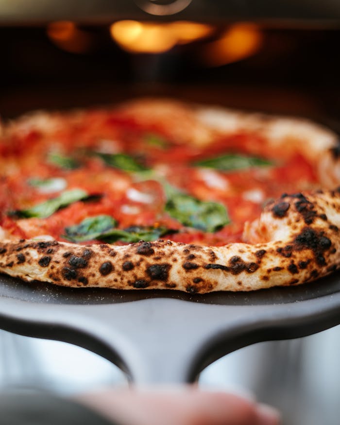 hero-img-02 Close-up of a fresh Neapolitan pizza with vibrant toppings and a crispy crust straight from the oven.