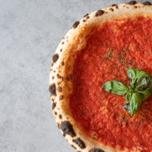 Freshly baked Margherita pizza with basil and tomato sauce, top view.